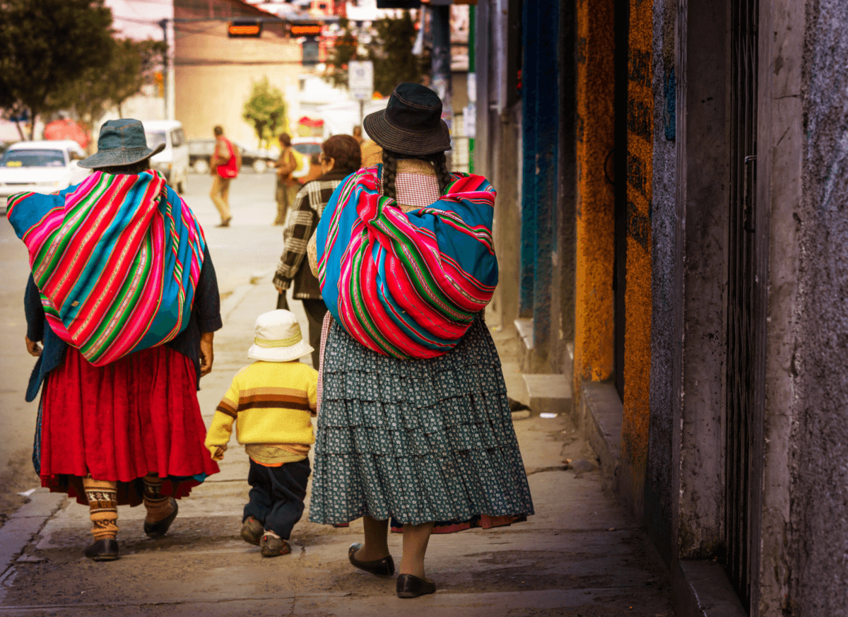 2 bolivian women walking with colourful bags on their back